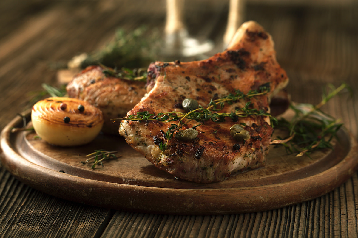 Pork chops with herbs on wood plate