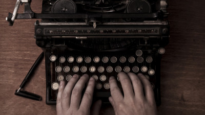 Man typing on old typewriter on wood