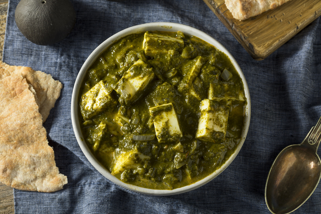 palak paneer in bowl with bread and spoon