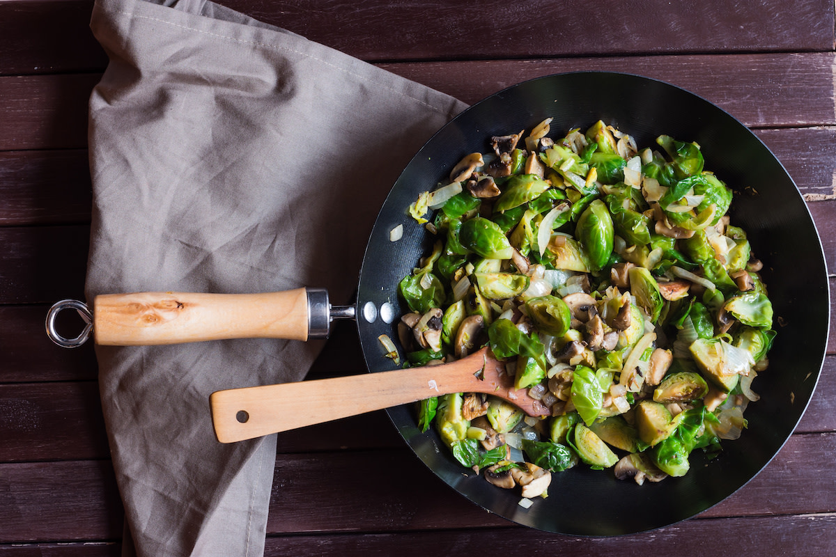 Sautéed vegetables in pan with wooden spoon and kitchen towel 