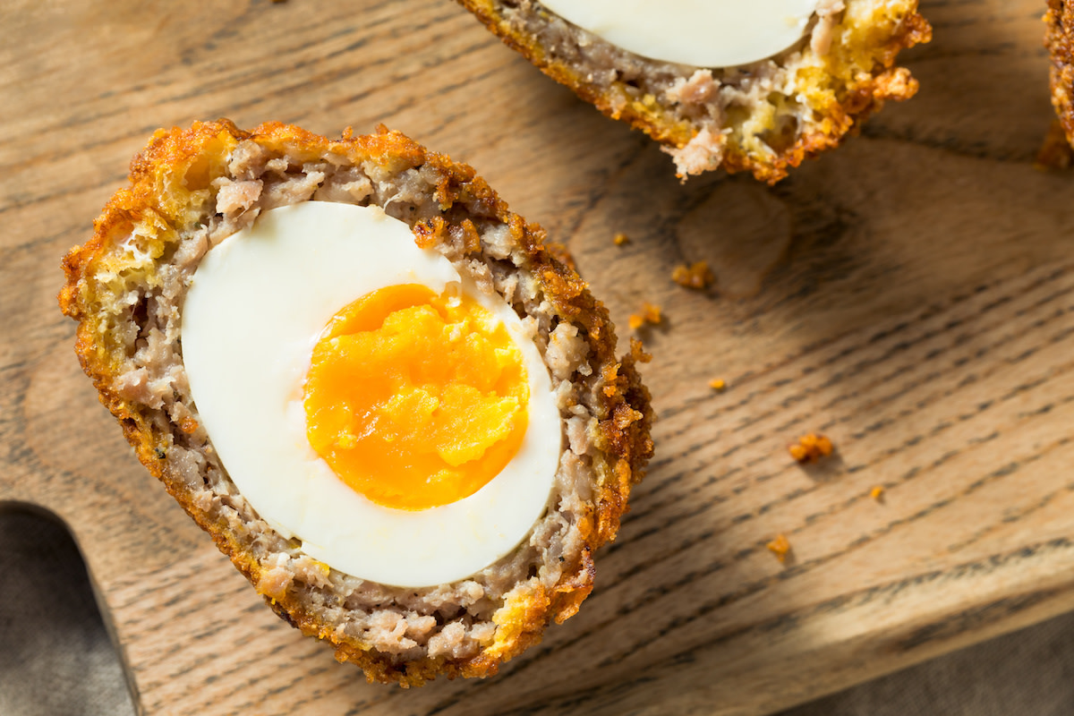 Scotch egg up close on wooden cutting board