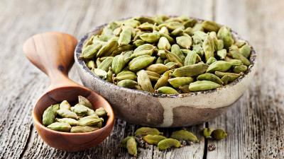 Cardamom in bowl on wooden background