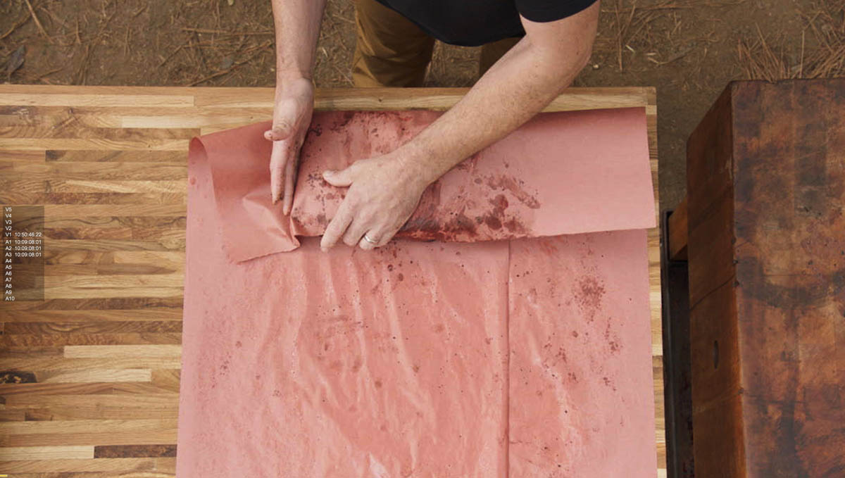 Aaron Franklin wrapping meat in red paper step 1