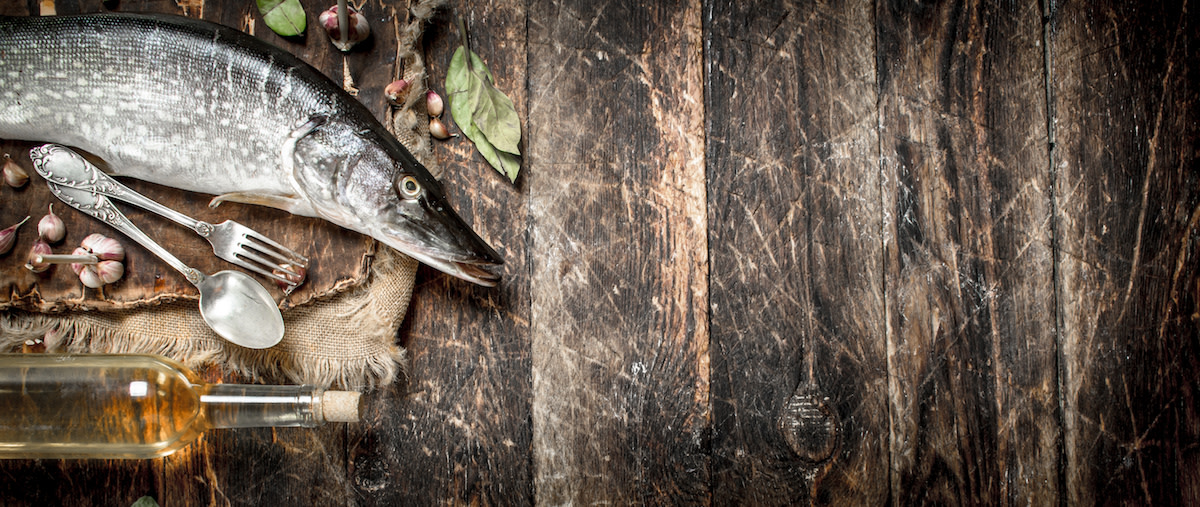 Raw whole pike fish on wood with herbs and oil