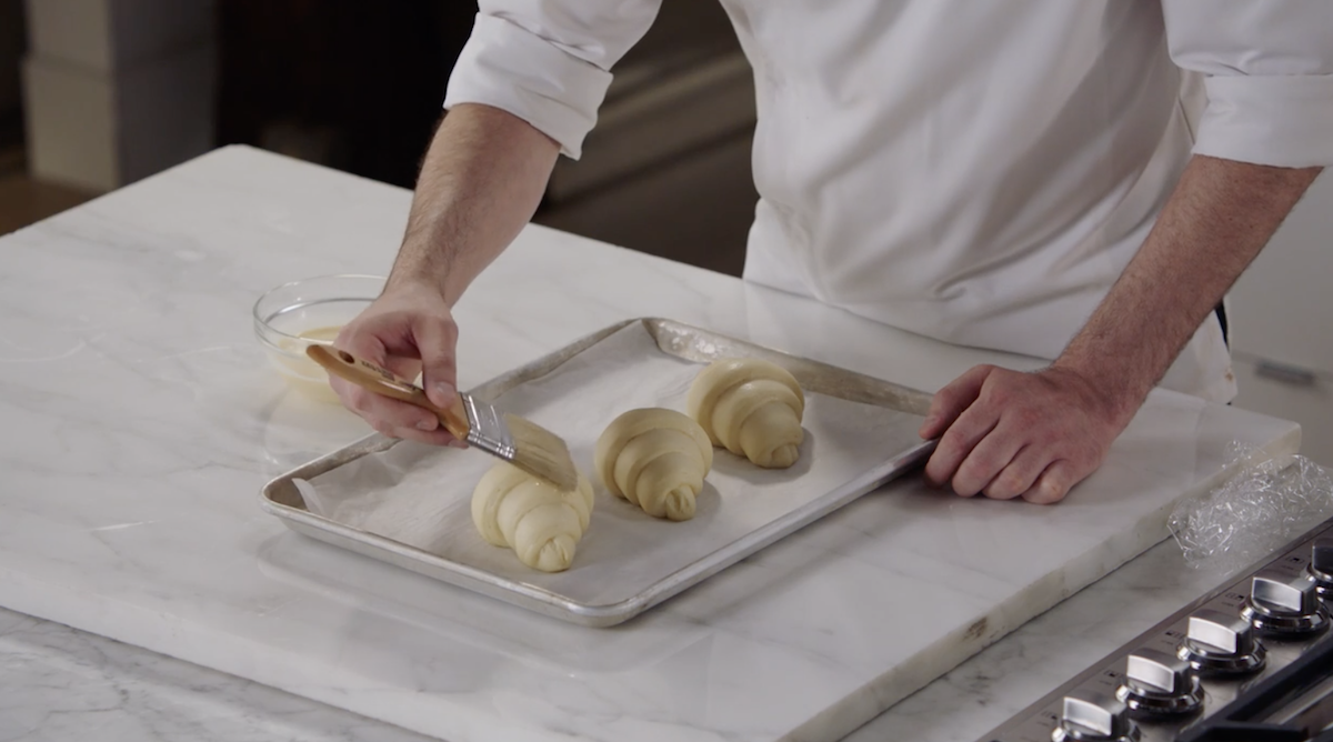 Dominique Ansel brushing egg wash on croissants