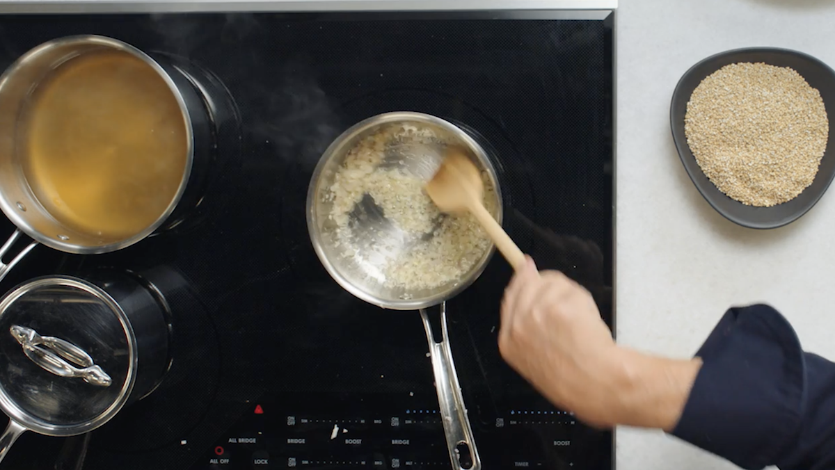 Wolfgang Puck stirring garlic and shallots into pot