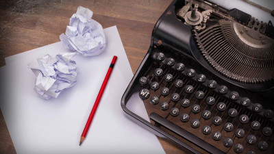 old typewriter with crumpled paper and red pencil