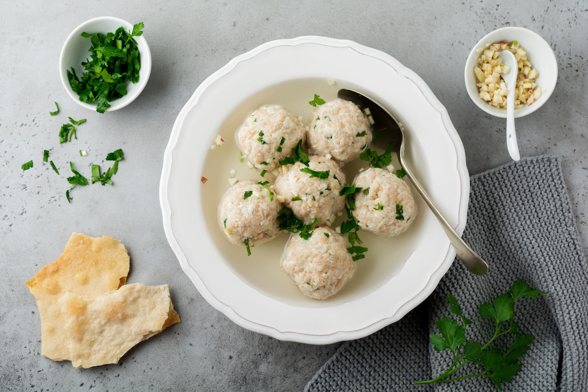 Matzah ball soup with parsley on gray table