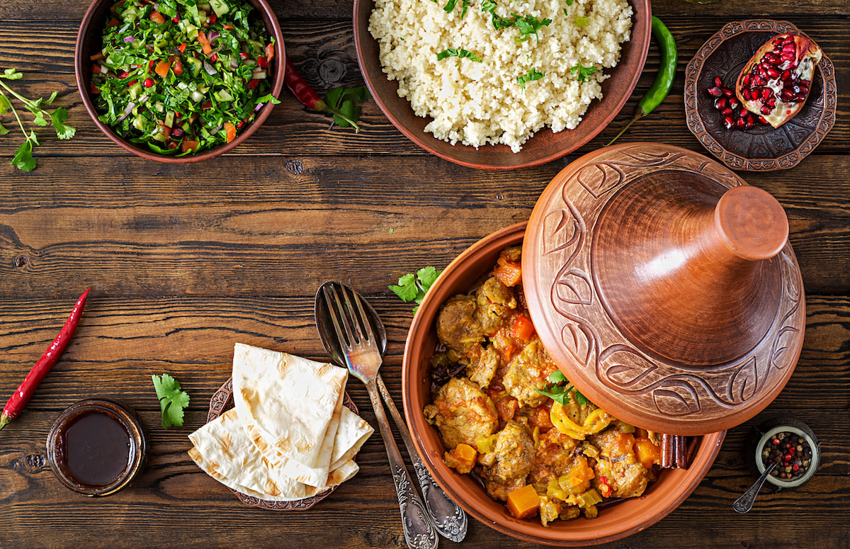 Tagine with food and ingredients on wood table