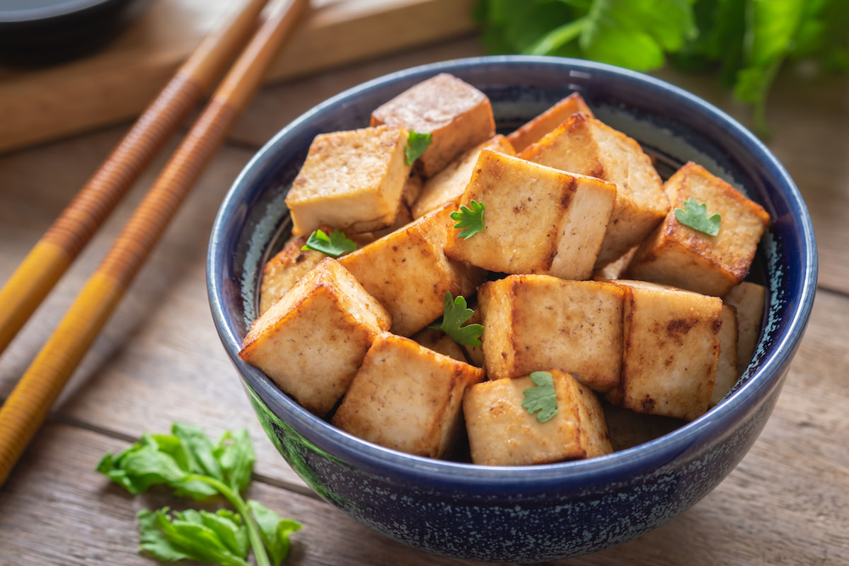 Cooked tofu in bowl with chopsticks and herbs