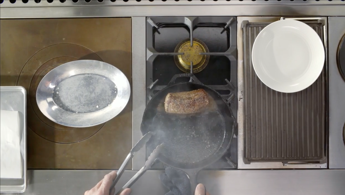 beef being cooked on cast iron skillet