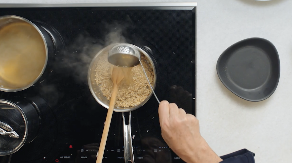 Wolfgang Puck pouring broth into oats on stove