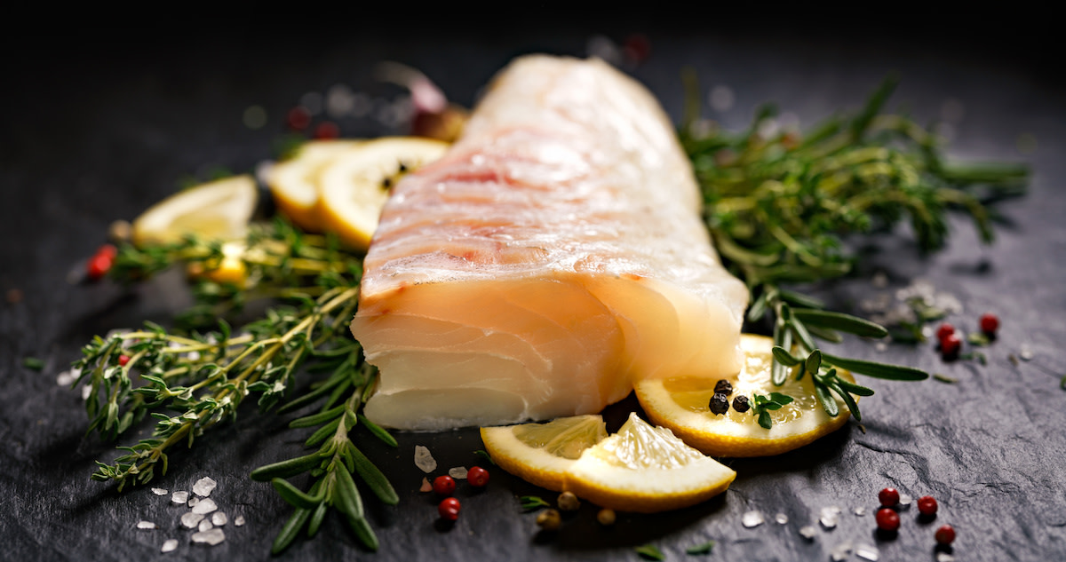 Raw cod filet on herbs and lemons 