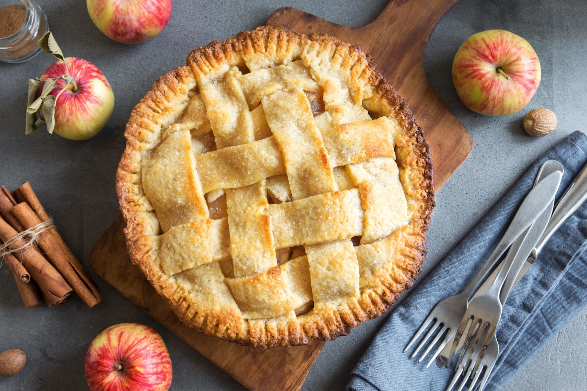 apple pie on wood board with whole apples