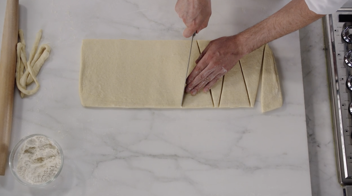 Dominique Ansel cutting croissant dough into triangles