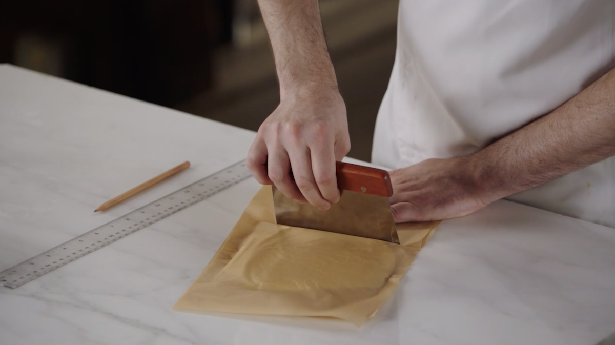 Dominique Ansel using dough scraper to shape butter