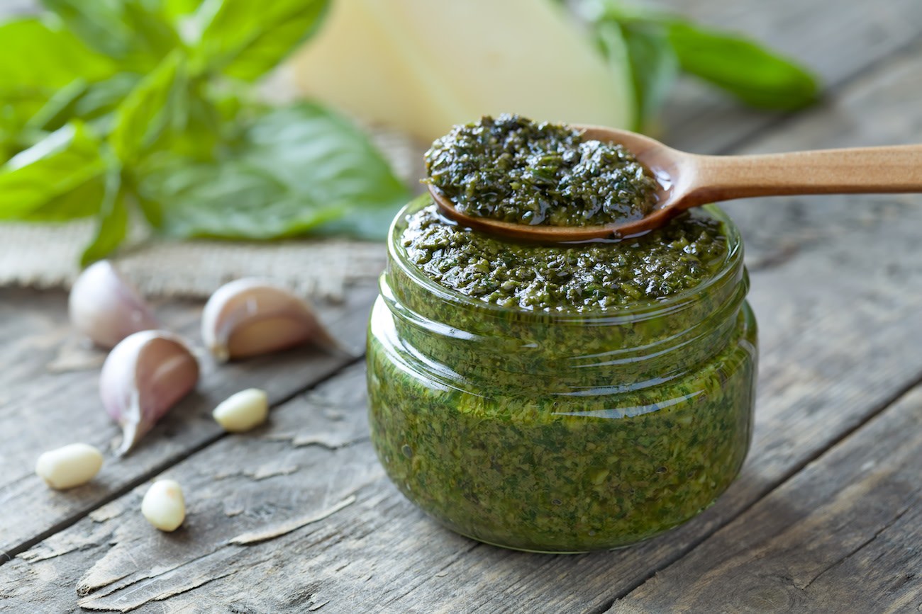 A spoonful and jar of fresh basil pesto