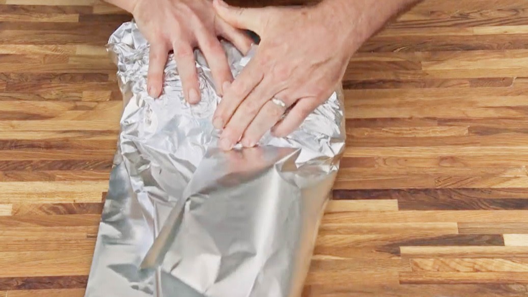 Aaron Franklin smoothing out tinfoil on wood table