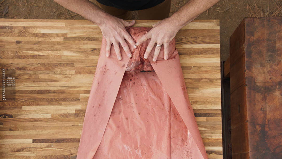 Aaron Franklin wrapping meat in red paper step 3