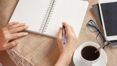 Women writing on notebook with coffee on burlap