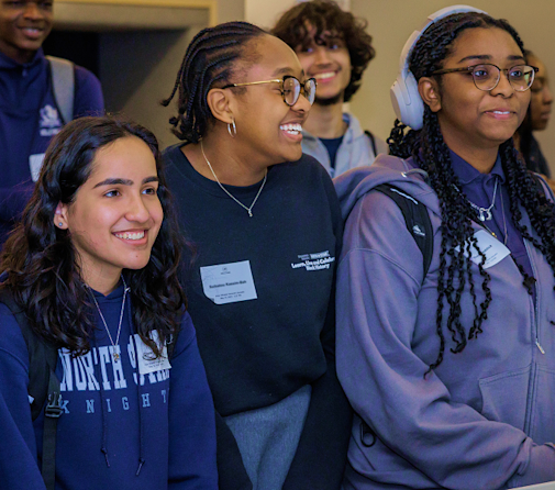 Three students in Audible's Future Leader program stand side by side, smiling, as they look at something off camera. 