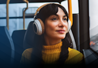 A woman wearing headphones while riding on a bus.