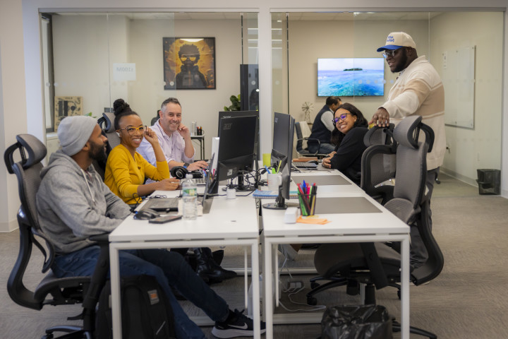 A group of employees at ABF Creative sits in their office at their desks. 