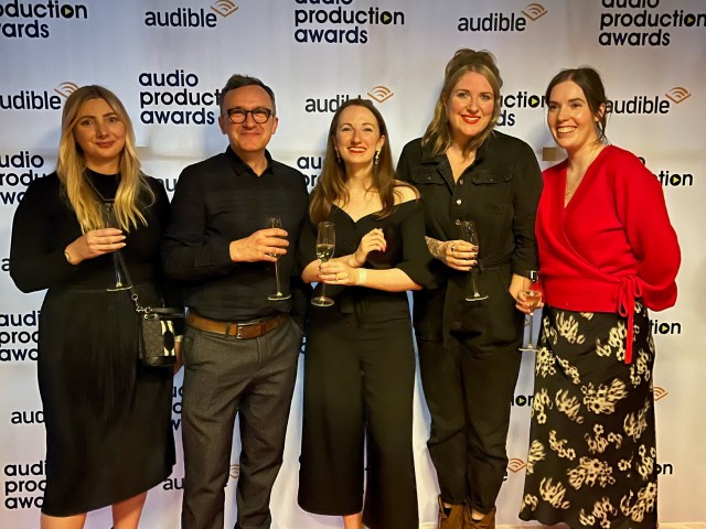 A group of five people are standing in front of a backdrop that says "Audio Production Awards" 