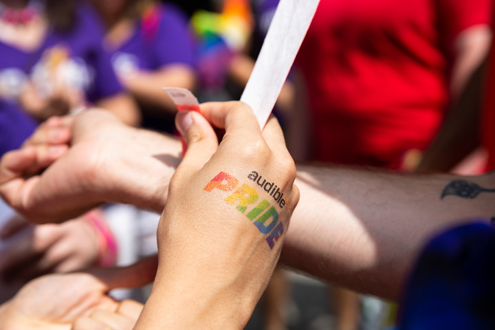 A close up of a hand with an Audible Pride temporary tattoo on the back of it.
