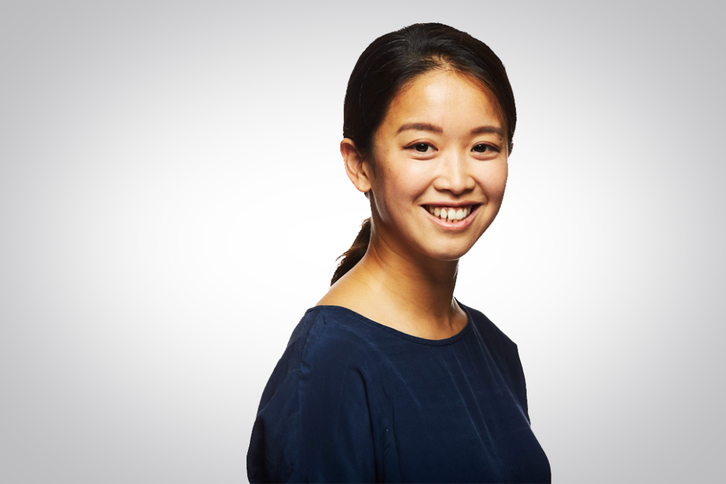 Jiun Kim is standing diagonally to the camera, smiling, and wearing a dark blue shirt.