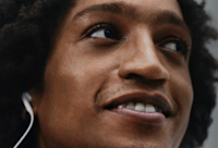 An image of a man listening to Audible on headphones while smiling.