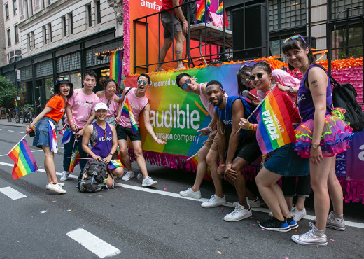 Several people posing in front of the Audible sign on a NYC Pride March parade float.