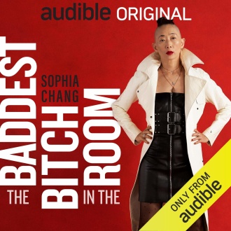 Sophia Chang stands in a power pose--legs spread slightly, hands on hips--and gazes directly into the camera. She is wearing a black leather dress, a white trench coat and gold jewelry. The background is read. The words "Audible Original" appear across the top in black and white. The title, "The Baddest Bitch in the Room" appear in white vertically.