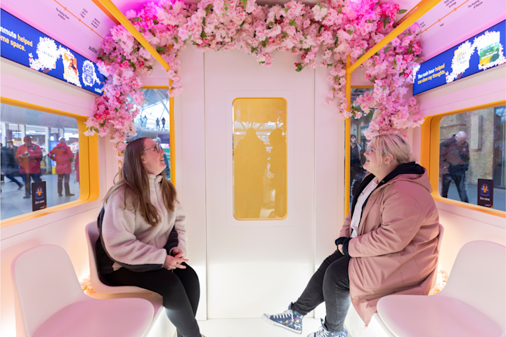 A photo of two visitors to King's Cross station seated inside of Audible's wellness-themed "Zen" carriage.