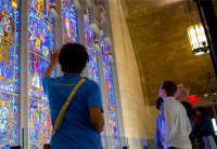 A group of 4 people are looking at the Innovation Cathedral's stained glass windows depicting multiple people throughout history who have contributed their own innovations in science and the arts.