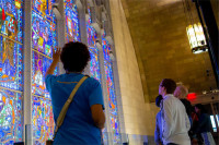 A group of 4 people are looking at the Innovation Cathedral's stained glass windows depicting multiple people throughout history who have contributed their own innovations in science and the arts.