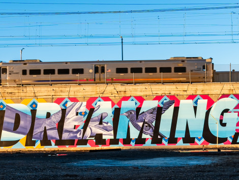 portion of a mural with the word "dreaming" under a bustling train station