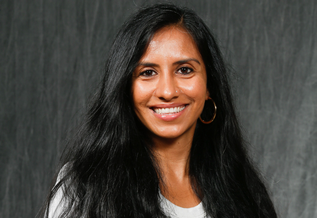 A headshot of Suemyra Shah, who's wearing a white shirt and hoop earrings. She's smiling. 