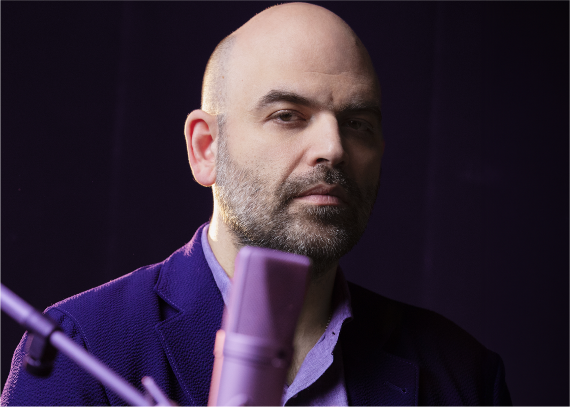 Roberto Saviano sits at a microphone in an Audible studio.