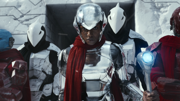 Group of four futuristic warriors in silver armor; one holding a staff with a glowing orb, others wearing helmets.