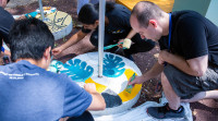 Several Audible employees and Newark artists paint leaves and other designs on the cement based of solar lights.