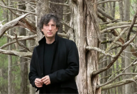 Neil Gaiman standing in a forest
