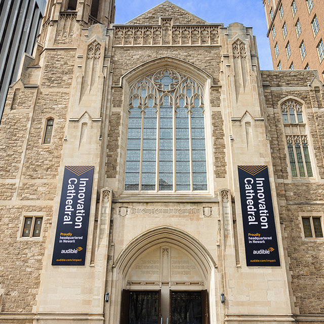 The front of a cathedral with two posters on its front that say "Innovation Cathedral".