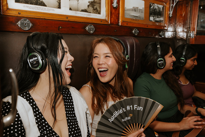 Fans aboard the Audible Express listened to scenes from “Harry Potter and the Sorcerer’s Stone.” One of the people is holding an unfolded fan that says "Audible's #1 Fan."