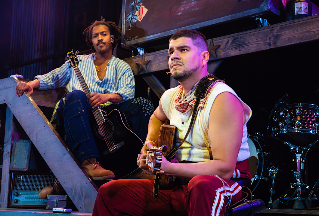 Nygel D. Robinson and Brian Quijada sit together onstage during a performance of “Mexodus.”