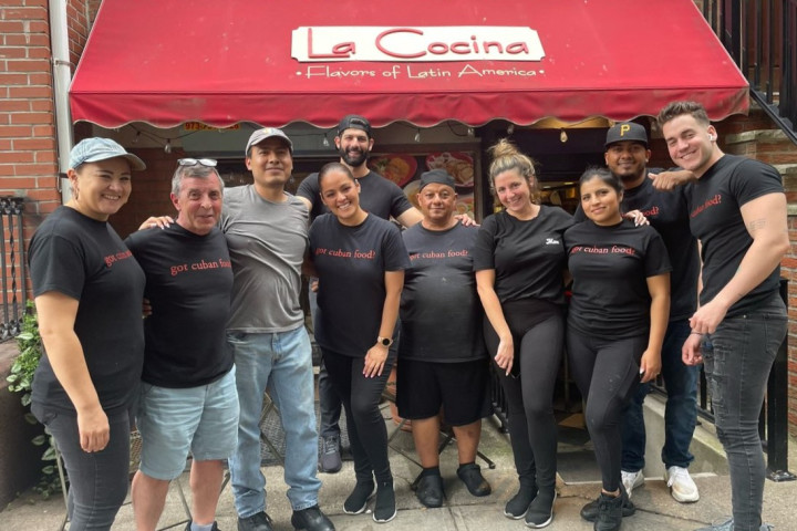 A group of people wearing La Cocina t-shirts post outside La Cocina restaurant. 