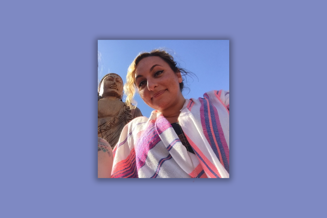 Audible employee Amy Garas is featured outside below a statue of buddha wearing a colorful striped shirt.