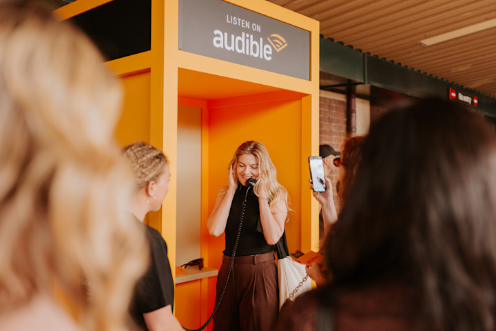 A woman standing in an interactive phone booth, listening to audio clips and recording messages describing what Harry Potter house they were in and why.