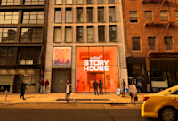 A rendering of the exterior of Audible Story House. The interior is partially visible behind a large, orange window.