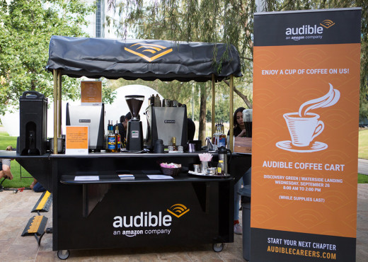 A large coffee cart with an Audible sign next to it.